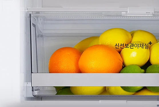 냉장고 내부의 투명한 서랍에 오렌지, 레몬, 라임이 담겨 있습니다. 서랍 위쪽에 신선보관야채실이라는 텍스트가 표시되어 있습니다.
